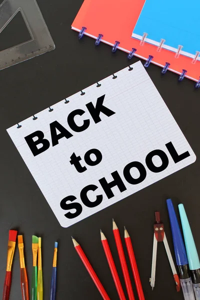 Nápis černý školní tabule s bílou křídou, různé barevné šablony, barvy, tužky, pera. Zpět na školní koncept, pohled shora — Stock fotografie