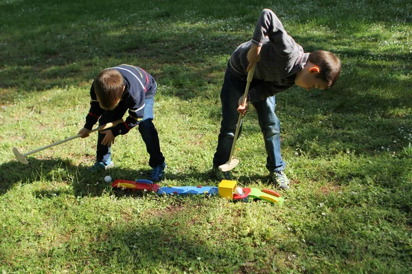 外の芝生で木のミニゴルフをしている2人の就学前の男の子夏の屋外ゲームの概念 — ストック写真