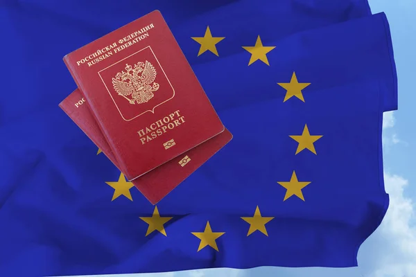 Zwei russische Pässe gegen die schwenkende blaue Flagge der Europäischen Union — Stockfoto