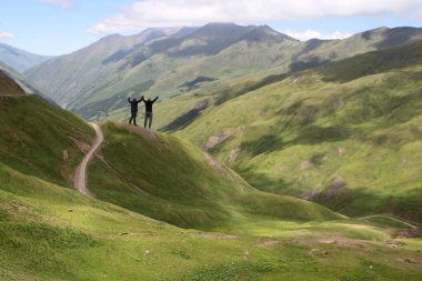 iki turist, erkek standı, silah Bear Cross Pass, Gürcistan dağları, alp çayırları, 2700 metre kaldırdı