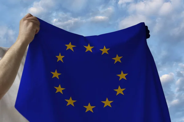 구름과 푸른 하늘에 대한 남성 손에 유럽 연합 (EU)의 국가의 아름다운 국기 — 스톡 사진