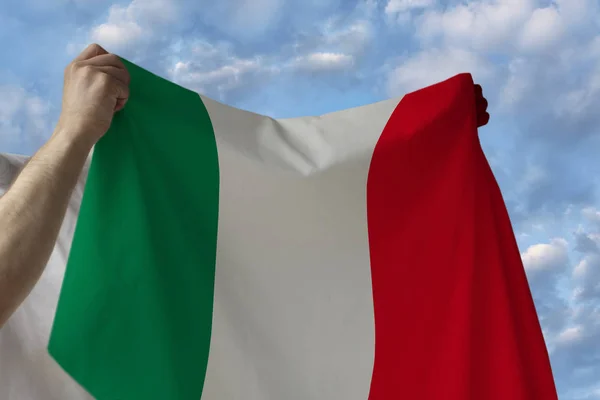 Beau drapeau national du pays d'Italie entre les mains des hommes contre le ciel bleu avec des nuages — Photo