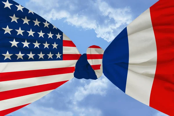 national flag of America is firmly tied to a knot with the national flag of France against the blue sky with clouds, the concept of friendship, unity, cooperation, international union