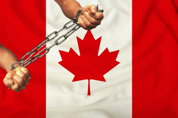 men\'s hands chained in heavy iron chains against the background of the flag of Canada on a gentle silk with folds in the wind, the concept of the movement in support of human rights