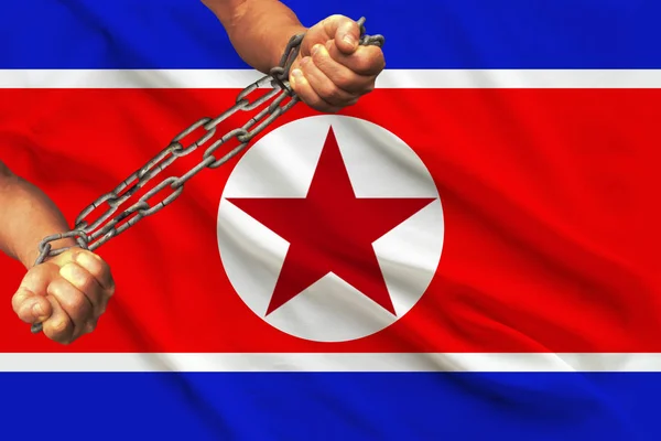 Manos de hombres encadenadas en pesadas cadenas de hierro sobre el fondo de la bandera de Corea del Norte sobre una suave seda con pliegues en el viento, el concepto de movimiento en apoyo de los derechos humanos —  Fotos de Stock