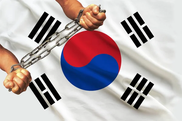 Manos de hombres encadenadas en pesadas cadenas de hierro sobre el fondo de la bandera de Corea del Sur sobre una suave seda con pliegues en el viento, el concepto de movimiento en apoyo de los derechos humanos — Foto de Stock