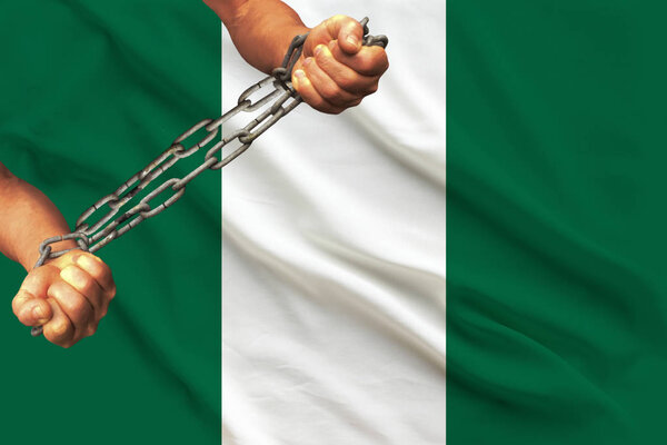 male hands chained in heavy iron chains against the background of the flag of Nigeria on a gentle silk with folds in the wind, the concept of the movement in support of human rights