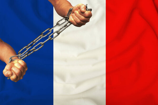 men's hands chained in heavy iron chains against the background of the flag of France on a gentle silk with pleats in the wind, the concept of the human rights movement