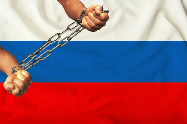men\'s hands chained in heavy iron chains against the background of the flag of Russia on a gentle silk with folds in the wind, the concept of the movement in support of human rights