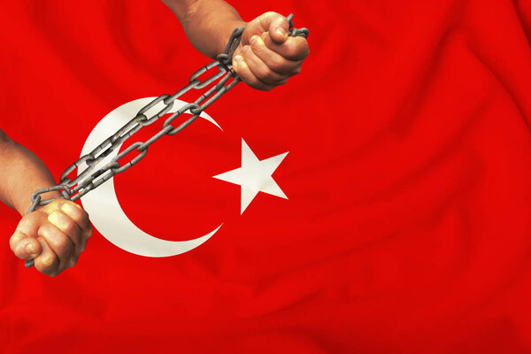 male hands chained in heavy iron chains against the background of the Turkey flag on a gentle silk with folds in the wind, the concept of the human rights movement