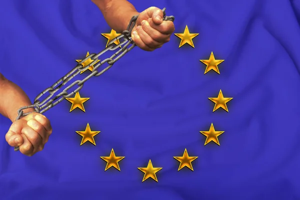 Руки, скованные тяжелыми железными цепями на фоне флага Европейского Союза по шелку, концепция правозащитного движения — стоковое фото