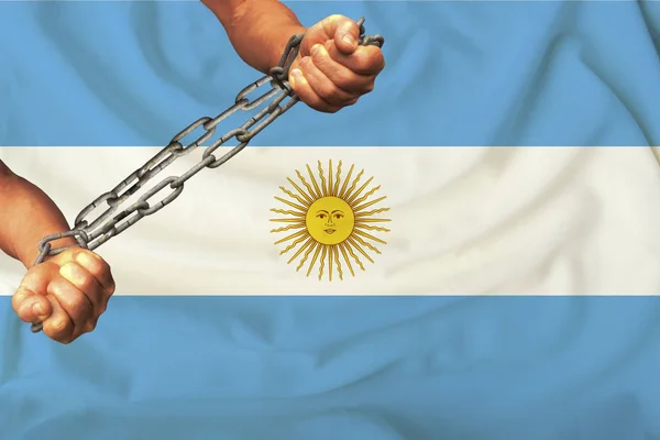 Manos masculinas encadenadas en pesadas cadenas de hierro en el trasfondo de la bandera del estado de la seda argentina, el concepto del movimiento de derechos humanos — Foto de Stock