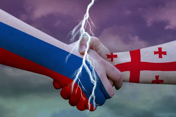 Handshake with the images of the flags of Russia and Georgia with a crack, the concept of international conflict — Stock Photo, Image