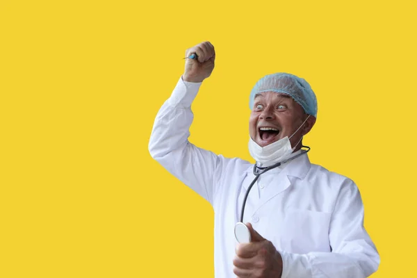 Чоловічий лікар у білому пальто і шапка тримає в руці стетоскоп, вираз і радість, на жовтому тлі, ізольований, копіювати простір — стокове фото