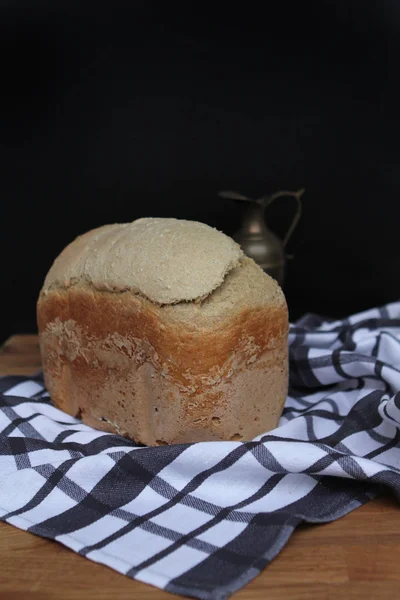 Pan de centeno recién horneado con una jarra de vino en un blanco con una servilleta negra — Foto de Stock