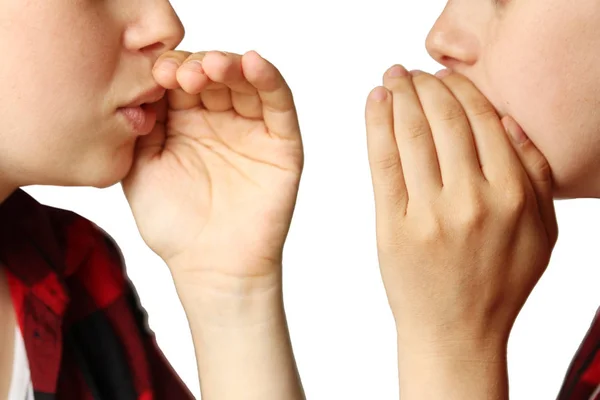 Dos niñas, cubriéndose la boca con las palmas de las manos, susurran sobre algo sobre un fondo blanco aislado, primer plano, concepto, aislar —  Fotos de Stock