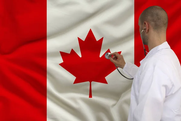 Male doctor in white coat applied a medical instrument with a stethoscope to the national flag, back view, concept, copy space — Stock Photo, Image