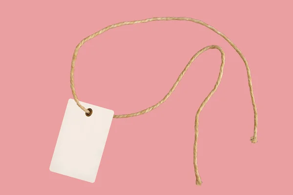 Pusty papierowy znacznik ceny lub etykieta w stylu retro na pięknym skręconym sznurku, odizolowanym na różowym tle — Zdjęcie stockowe