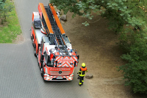 Brandman i en ljusgul Uniform går till tjänsten klarröd brandbil med en inskription i tyska Frankfurt Fire service — Stockfoto