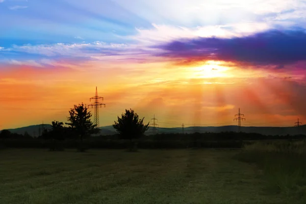 Naturalnym krajobrazem z zielonym polem letnim i pięknym romantycznym zachodem słońca z promieniami — Zdjęcie stockowe
