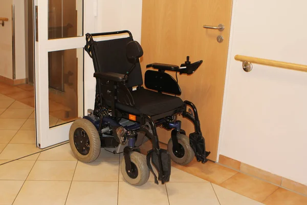 Одинокая черная инвалидная коляска стоит пустым у стены — стоковое фото