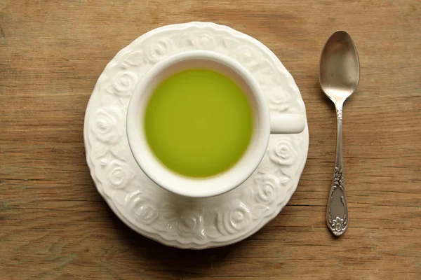 Top view. green tea in a white cup with a saucer and a spoon on a wooden table — Stock Photo, Image