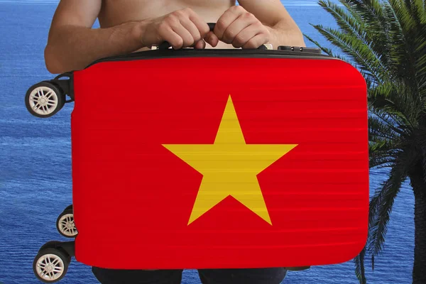 Турист держит двумя руками чемодан с национальным флагом Вьетнама, символом отпуска, иммиграции, политического убежища — стоковое фото