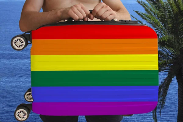 Mann hält mit zwei Händen einen Koffer mit lgbt Regenbogenfahne, einem Symbol für Urlaub — Stockfoto