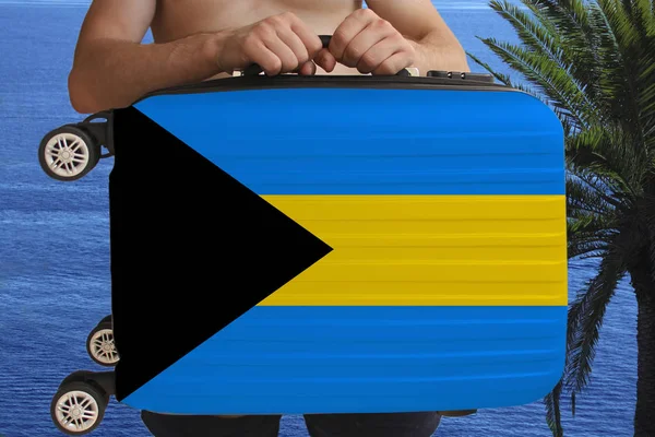 Tourist hält mit beiden Händen einen Koffer mit der Nationalflagge Bahamas, einem Symbol für Urlaub, Einwanderung, — Stockfoto