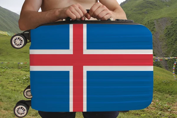 Tourist houdt met twee handen een koffer met de nationale vlag van IJsland, een symbool van het toerisme, immigratie, politiek asiel — Stockfoto