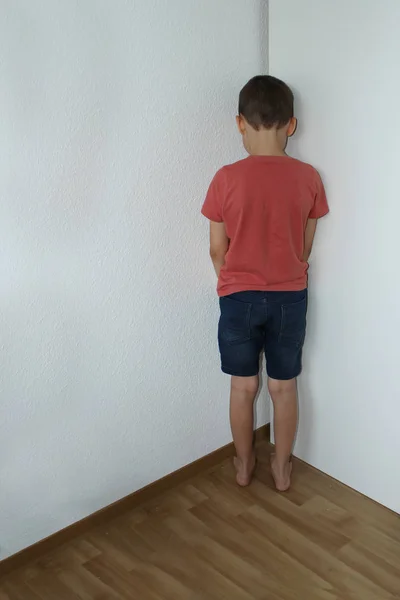 Chłopiec, młodszy uczeń, stojący w rogu, stoi na ścianie, ukarany przez rodziców za niewłaściwe postępowanie, koncepcja rodzicielstwa — Zdjęcie stockowe