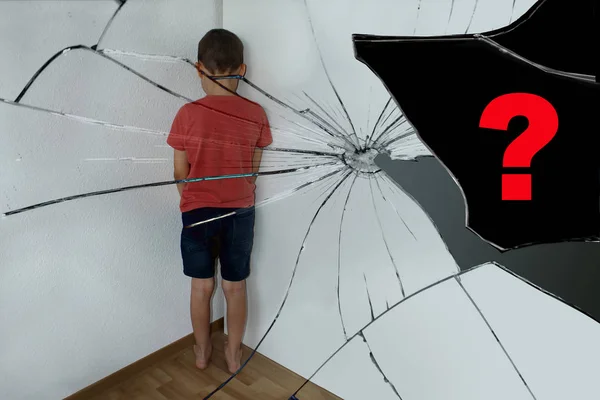 Наказанный мальчик, младший школьник, отражается в осколках разбитого зеркала, стоит в углу, поворачивается к стене, вопросительный знак — стоковое фото