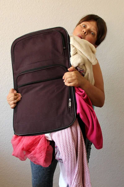 Kobieta posiada zatłoczone walizki, z których rzeczy wypadają, pojęcie wakacje, Podróże, turystyka — Zdjęcie stockowe
