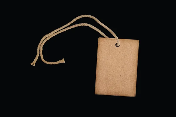 Пустой ценник бумаги или этикетка на красивом скрученном шнуре, изолированном на черном фоне — стоковое фото