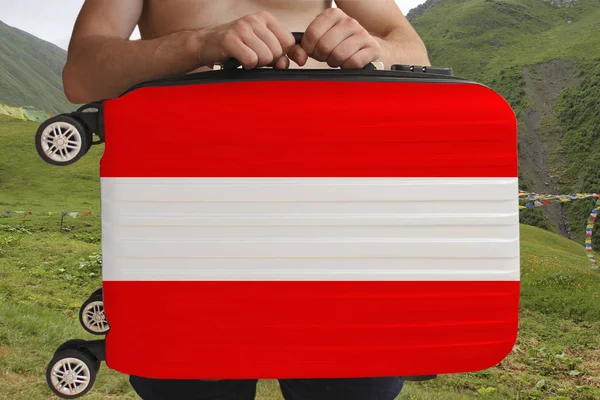 Tourist hält mit beiden Händen einen Koffer mit der Nationalflagge Österreichs, einem Symbol für Urlaub, Einwanderung — Stockfoto