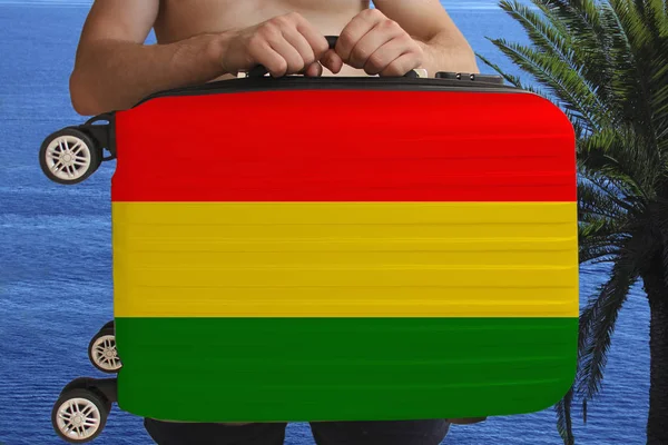 Tourist hält mit zwei Händen einen Koffer mit der Nationalflagge von Bolivien, einem Symbol für Urlaub, Einwanderung — Stockfoto