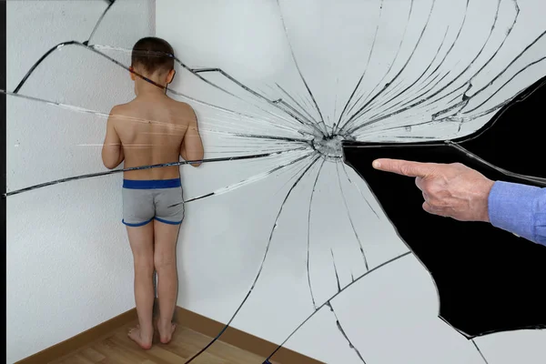 Um menino punido, um estudante júnior, refletido nos fragmentos de um espelho quebrado, está parado no canto, de frente para a parede, as mãos dos parentes são mostradas com um dedo, o conceito de humilhação. — Fotografia de Stock