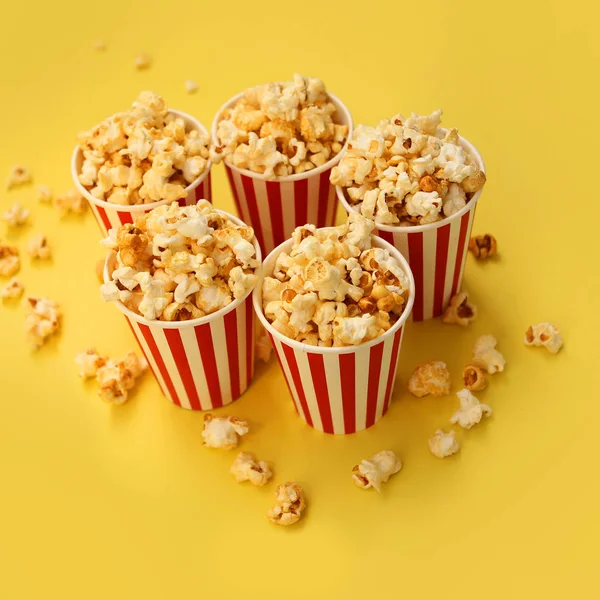 Cinco tazas de papel rojo y blanco con palomitas de maíz sobre un fondo amarillo — Foto de Stock