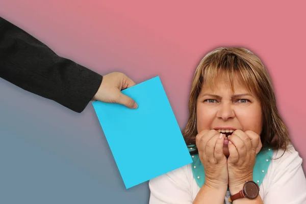 Mooie vrouw van middelbare leeftijd met een grimasde van stress en wanhoop bijt haar gebalde handen, de baas houdt een blauw vel papier, kopieer ruimte, close-up — Stockfoto