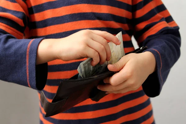 Niño, preescolar, estudiante de primaria, pone dinero, billetes, dólares, euros en una cartera de cuero, manos de cerca —  Fotos de Stock