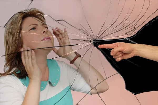 Mannelijke hand toont vinger met geaccusing gebaar op mooie middelbare leeftijd vrouw, lichte achtergrond van gebroken glas, close-up, kopieer ruimte — Stockfoto