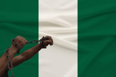 devlet bayrağının arka planına karşı kalın bir demir çar sarılmış kaslı erkek elleri, siyasi mücadele kavramı, suç, zulüm, hapis, insan özgürlüğünün ihlali