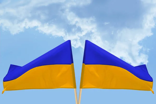 Duas bandeiras estatais da Ucrânia em um fundo de céu azul com nuvens — Fotografia de Stock