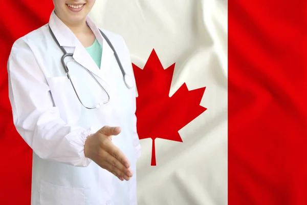 Young beautiful girl doctor with an open smile holds out his hand for greeting on the background of the national flag, concepts of health care, medicine — Stock Photo, Image