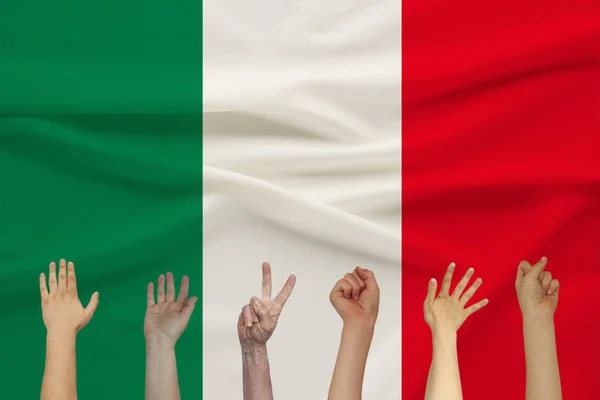 Πολλά ανυψώσει τα χέρια των ανθρώπων με φόντο μια έγχρωμη σημαία του μεταξιού με απαλές πτυχώσεις, αντίληψη της ενότητας των ανθρώπων — Φωτογραφία Αρχείου