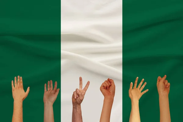 Muchas manos levantadas de la gente en el fondo de una bandera de seda de color del estado con pliegues suaves, concepto de unidad de la gente — Foto de Stock
