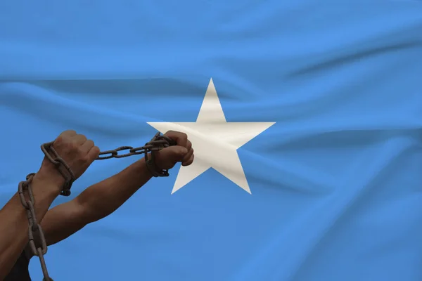 Devlet bayrağının arka planına karşı kalın bir demir çar sarılmış erkek kaslı kollar, suç kavramı, zulüm, hapis, insan özgürlüğünün ihlali — Stok fotoğraf