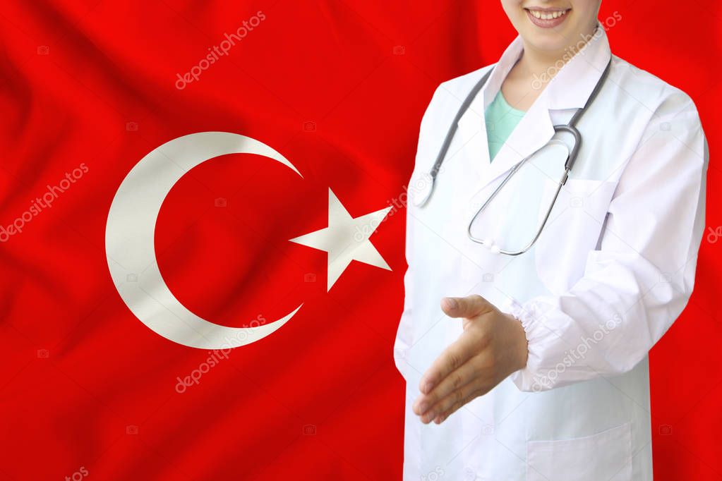 young beautiful girl doctor with an open smile holds out his hand for greeting on the background of the national flag, concepts of health care, medicine