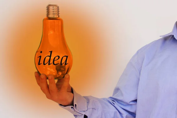 Forretningsmann i blå skjorte holder i hånden en stor lyspære av glass, konseptet elektrisitet, ide, kopirom – stockfoto