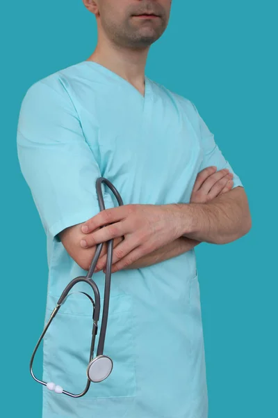 Αρσενικό γιατρό με μπλε στολή με επαγγελματικά ρούχα με ένα στηθοσκόπιο στα χέρια σε χρωματιστό φόντο, ιατρική αντίληψη, κοντινό-up, αντίγραφο χώρου — Φωτογραφία Αρχείου